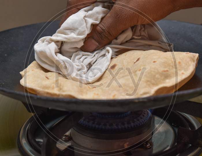 Making Roti (Indian Chapati) On Roti Tawa Made Of Wheat With Hand
