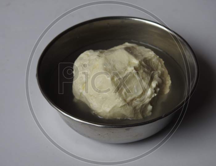 Butter ball from milk at home - home made butter in a cup and holding in a hand isolated on white background