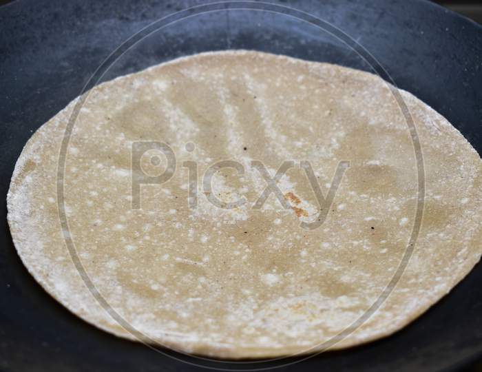 Making Roti (Indian Chapati) On Roti Tawa Made Of Wheat Dough