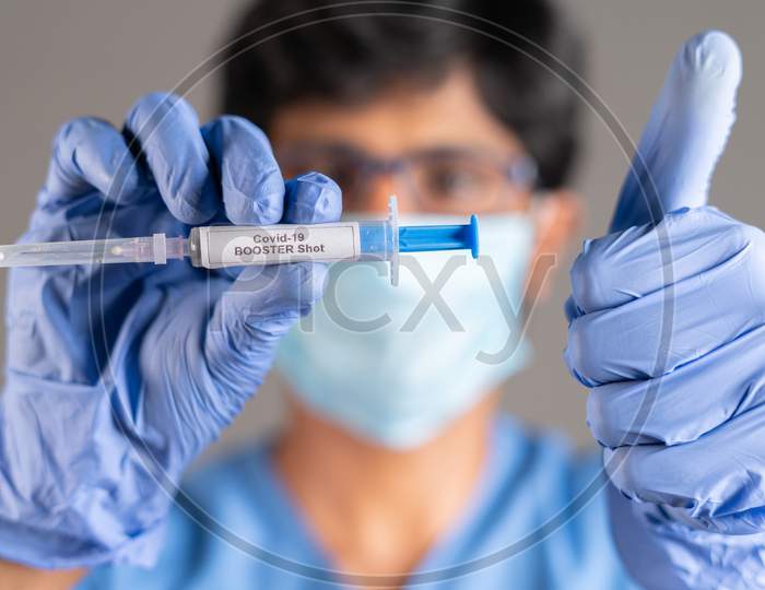 Close Up Of Doctor Hands With Covid-19 Booster Shot Syringe Showing Thumbs Up - Concept Showing Of Recommendation Of 3Rd Dose Vaccination For Immune Weakened People