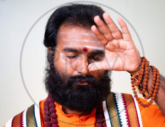 Close Up Head Shot Of Indian Holy Yoga Guru Or God Man Doing Nostril Breathing Or Nadi Shodhana Pranayama Exercise Or Yoga.