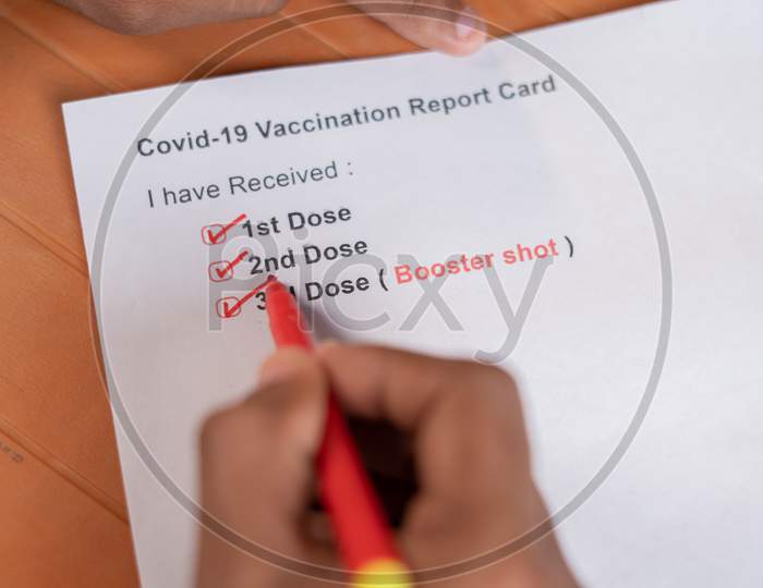 Pov Close Up Shot Of Hands Checking Covid-19 Vaccine Report Card And Ticking 3Rd Or Booster Dose After Vaccination