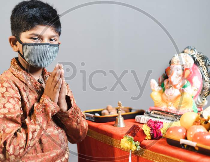 Young Kid With Medical Face Mask At Ganesha Festival With Traditional Dress Doing Namaste By Looking Camera During Coronavirus Covid-19 Pandemicvi