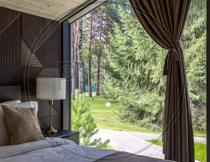 White Bed,  Quilt And Pillows In  Wooden Bedroom.  Hotel Bedroom.  Comfortable Bed With Soft Blanket In Stylish Room  With View On Green Forest