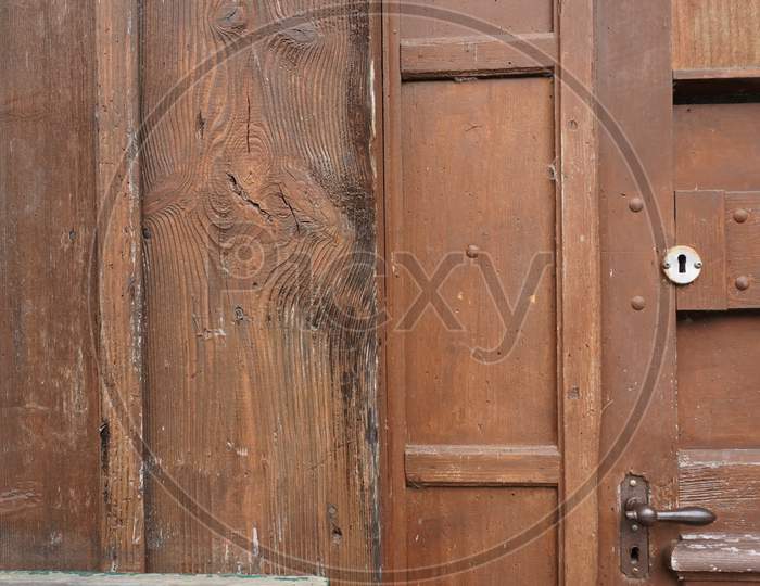 Closeup Of Brown Closed Door With Door Handle And Keyhole In Aged Wooden House.