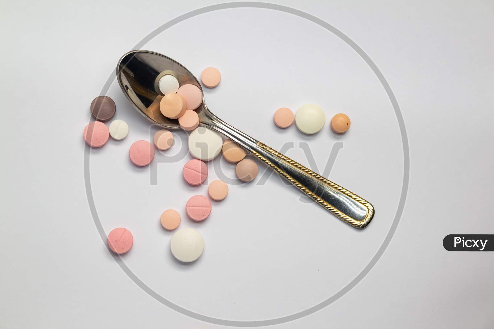 Colored Pills Or Medications On A Neutral Background Next To A Small Spoon.