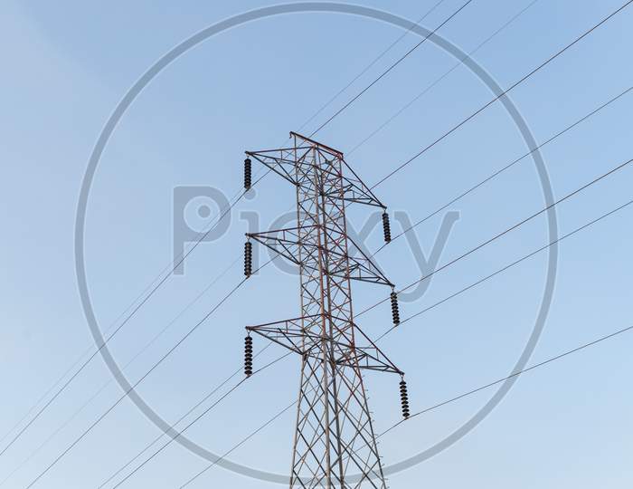 High-Voltage Power Lines Electricity Transmission Pylon On Blue Sky Background.
