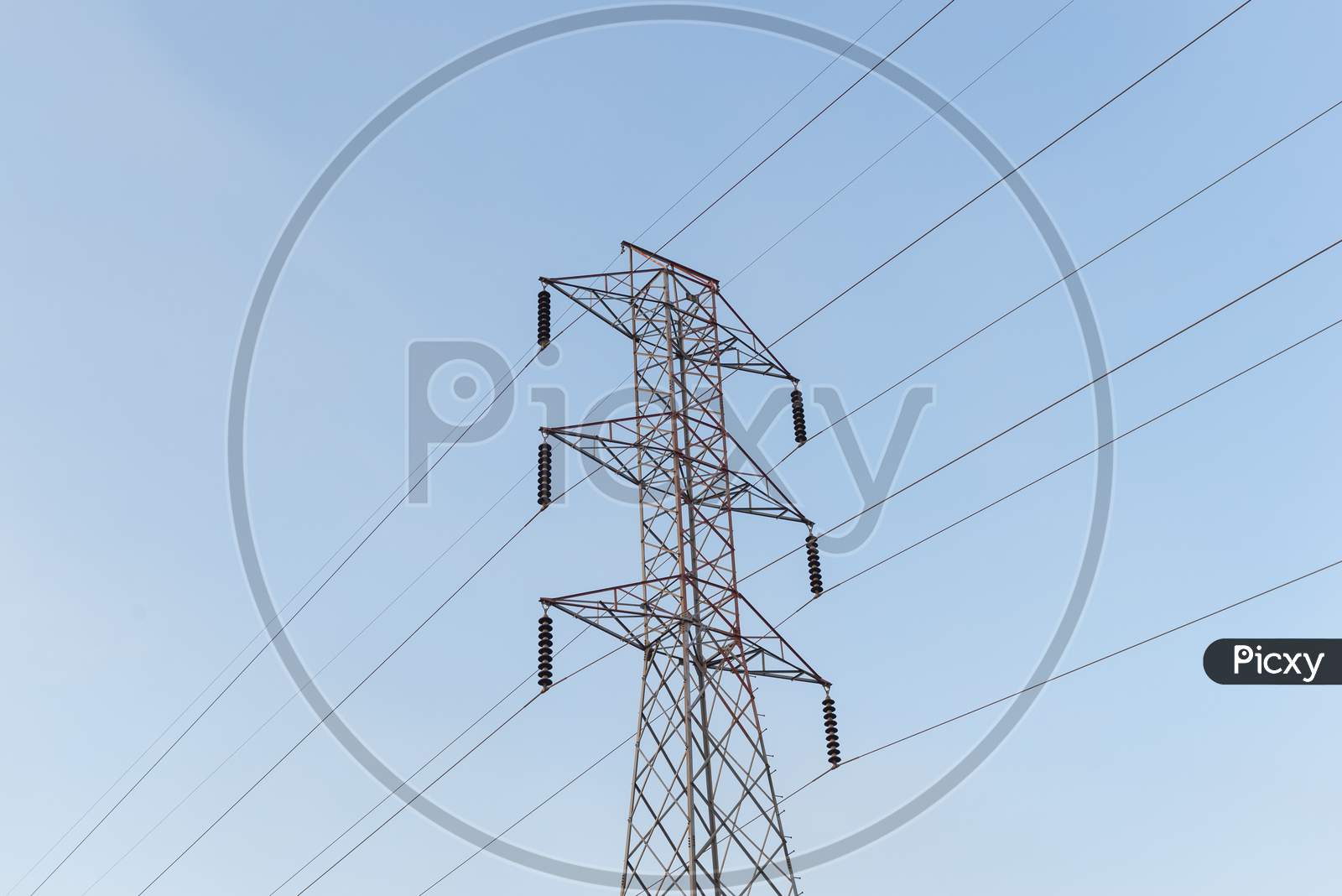 High-Voltage Power Lines Electricity Transmission Pylon On Blue Sky Background.