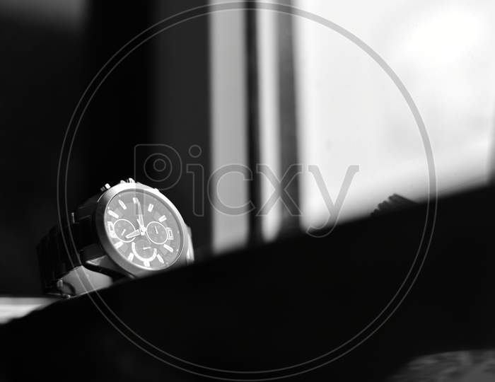 Men's stainless steel wrist watch on a flat surface near window