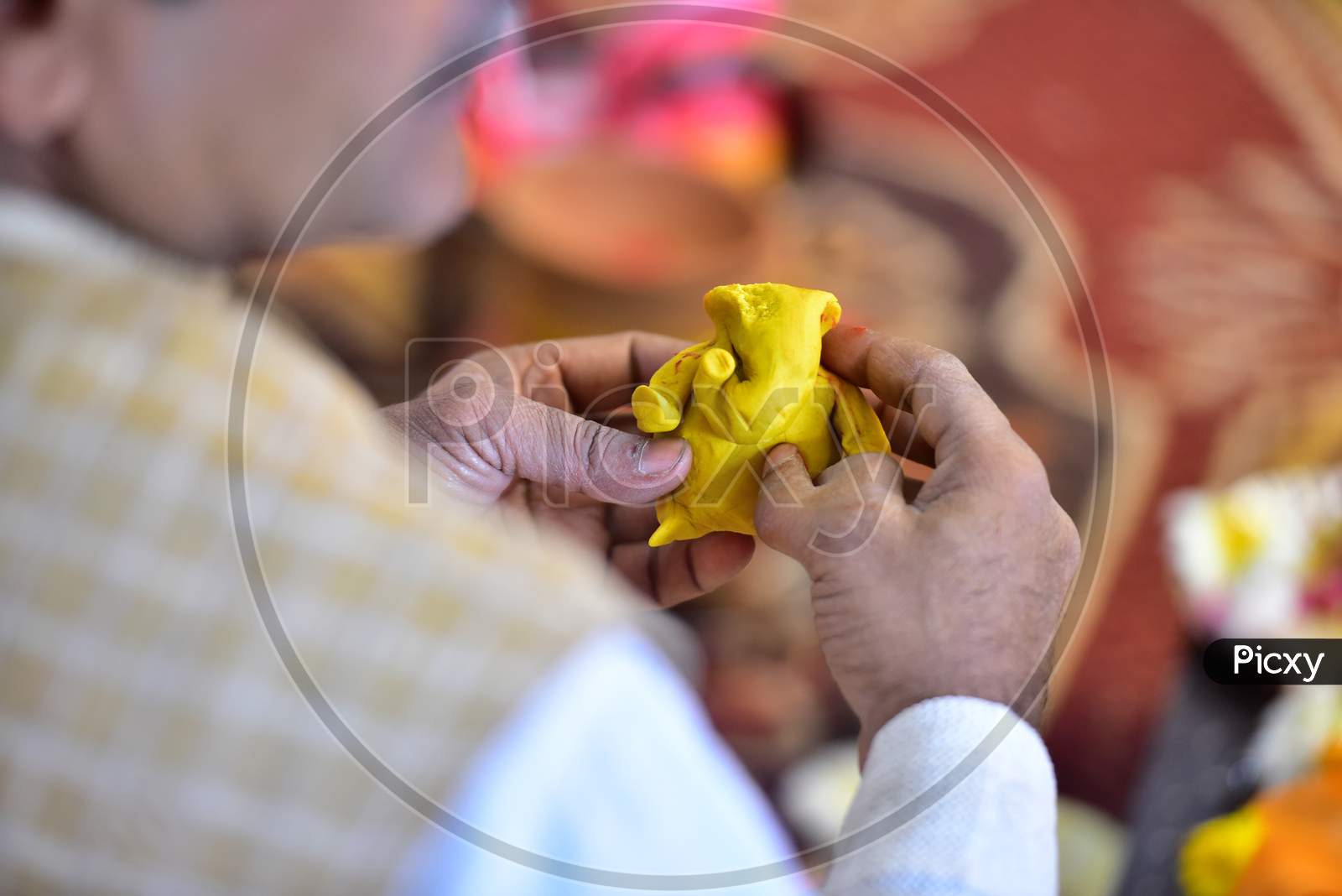An Indian hindu priest making lord Ganesha from flour mixed with turmeric power and ghee during a religious function