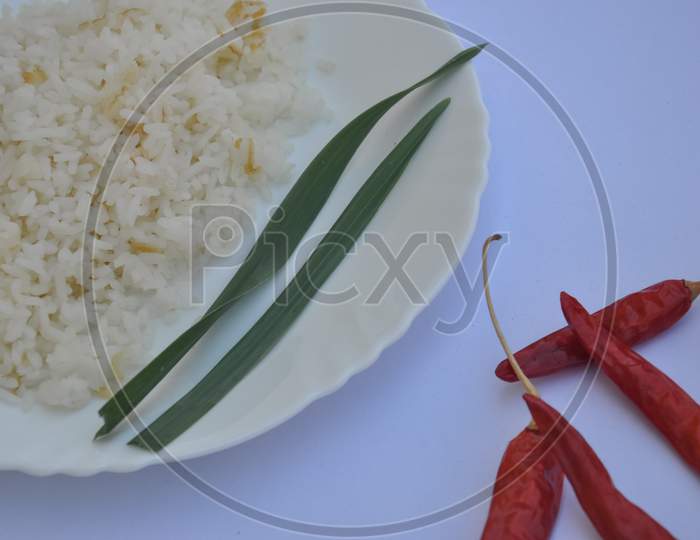 Closeup shot of rice in white plate with red chilli peppers isolated over white background