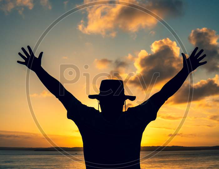 Silhouette Of A Man With A Hat During Sunset. Happiness Concept In Free Time.