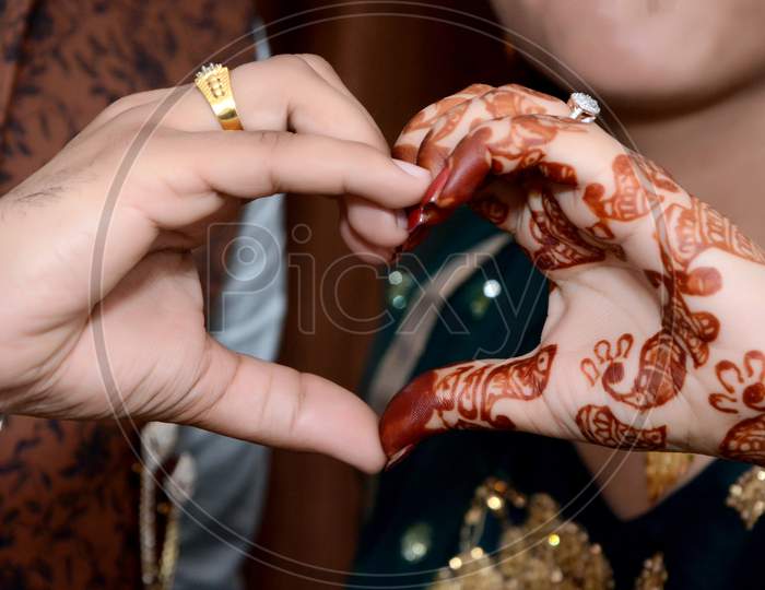 Young Newlywed Couple Making A Heart Gesture With Their Hands