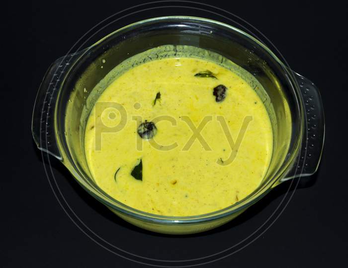 Kerala Onam Special Traditional Yellow Buttermilk Curry Also Known As Moru Curry, Pulissery, Kachiya Moru In Glass Bowl. Black Background