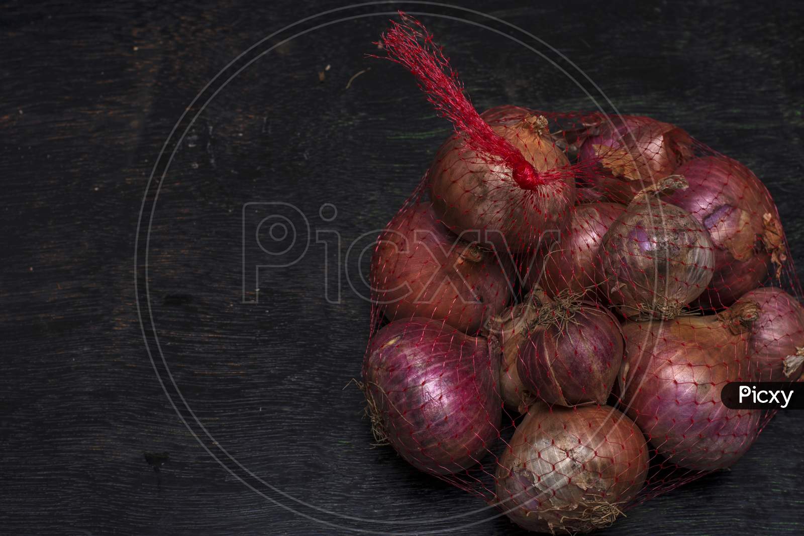 A Net Bag Full Of Onions On A Black Background With Selective Focus