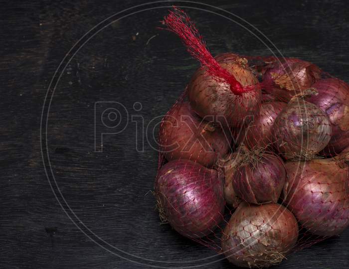 A Net Bag Full Of Onions On A Black Background With Selective Focus