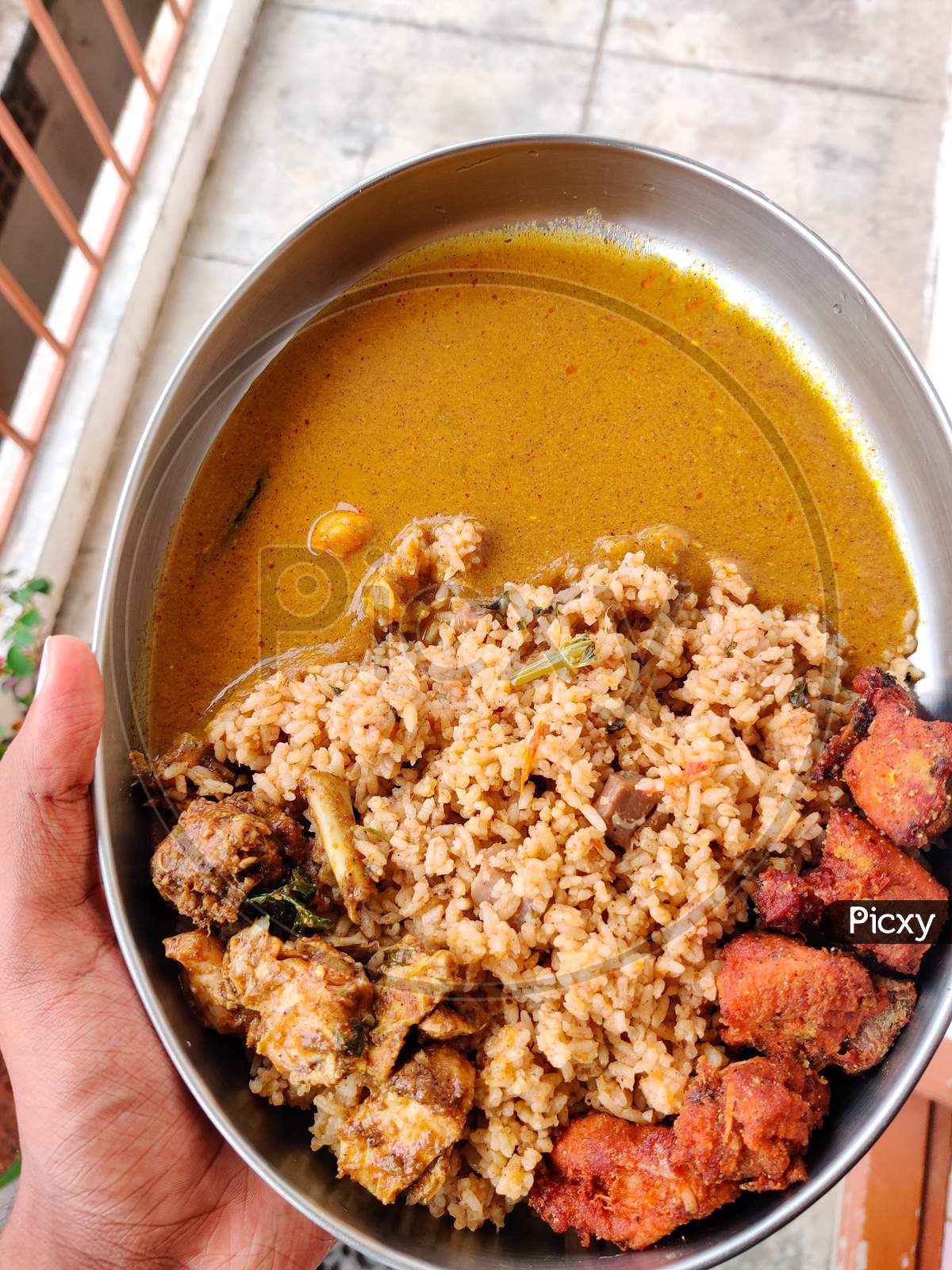 Male Hands Holding A Silver Plate Filled With Mutton Biryani, Chicken 65, Chicken Fry And Chicken Gravy. A South Indian Sunday Lunch.