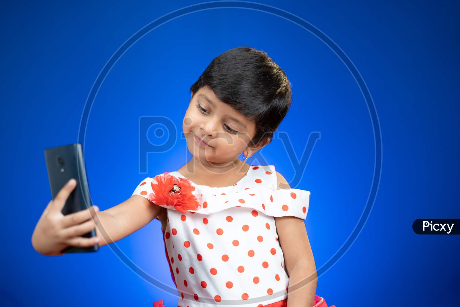Little Girl Kid Or Toddler Taking Selfie And Checking Photos From Mobile Phone On Blue Background - Concept Of Technology, Internet And Modern Lifestyle