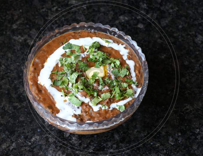 A wide shot of Dal makhani or daal makhni garnished with coriander leaves and butter