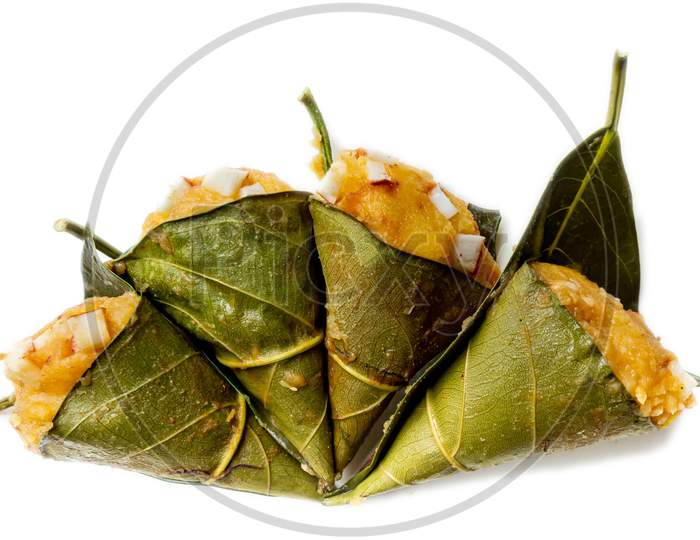 Traditional steamed ripe palmyra palm fruit cake wrapped with jackfruit leaves and sprinkled with coconut pieces. Steamed palmyra palm cake in isolated white background.