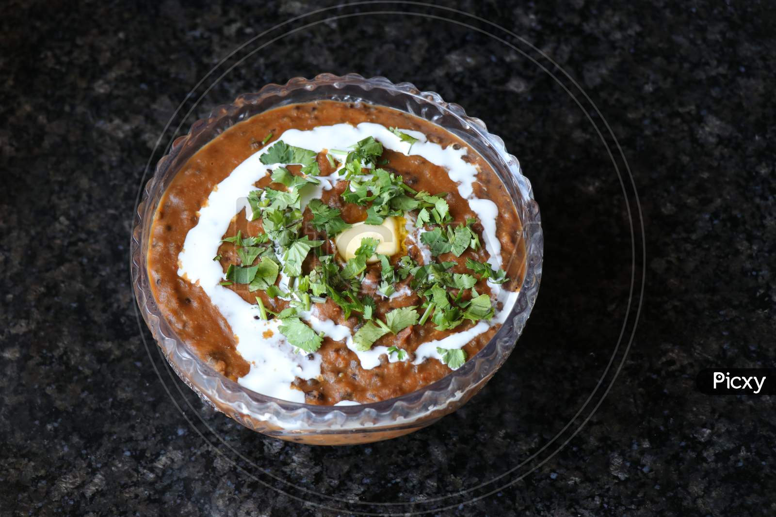A wide shot of Dal makhani or daal makhni garnished with coriander leaves and butter