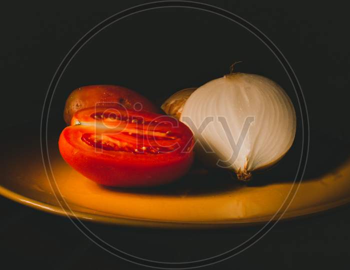 Tomatoes And Onions On A Yellow Plate. Still Life Effect Created With Light.