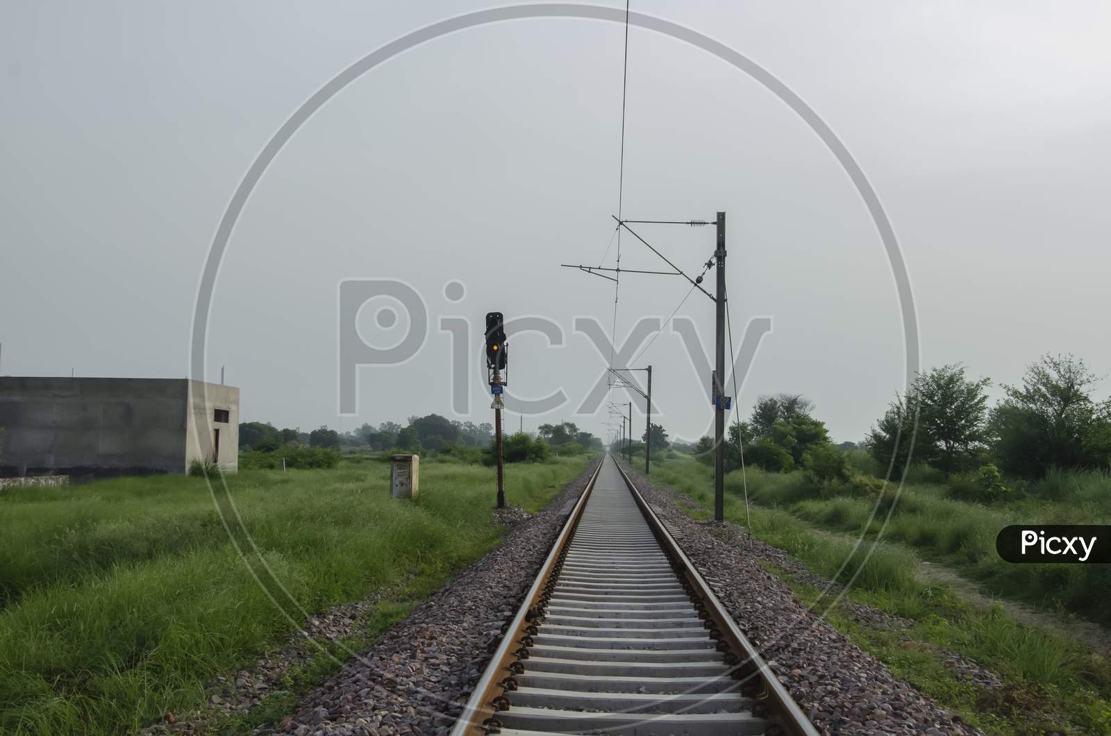 RAILWAY TRACK WITH LIGHT AND ELECTRIC POLE IN LANDSCAPE.