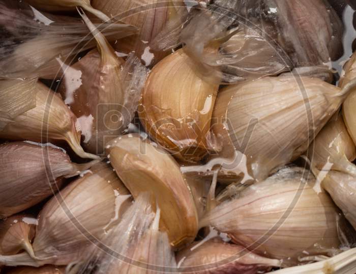 Garlic Cloves Soaked In Water. Seasoning Of Vegetable Origin For Food.