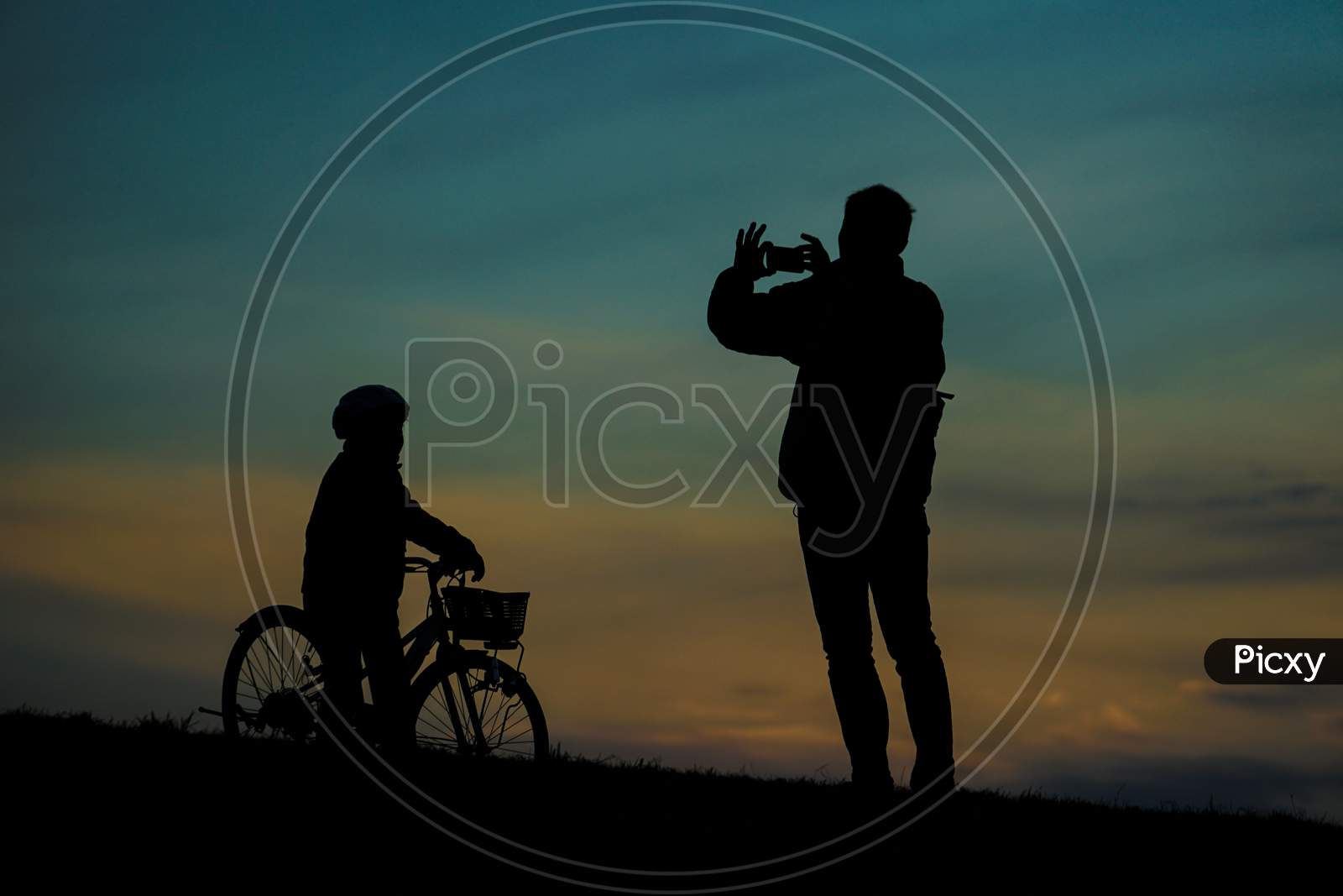 Silhouette Of Parent And Child Standing On Sunset Hill