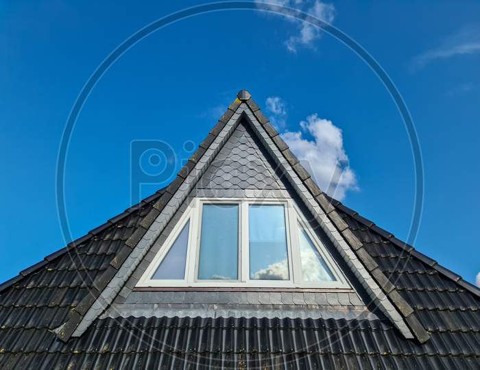 Open Roof Window In Velux Style With Black Roof Tiles And A Blue Sky Background.