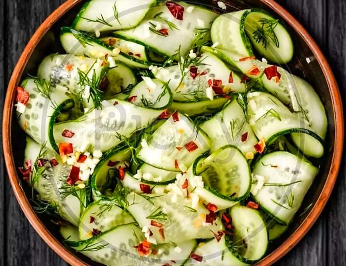 wood salad bowl and one cucumber decoration photo