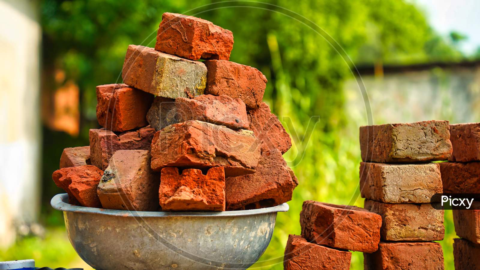 Image of Close Up Photo Of Small Pile Of Red Color Bricks In The Garden