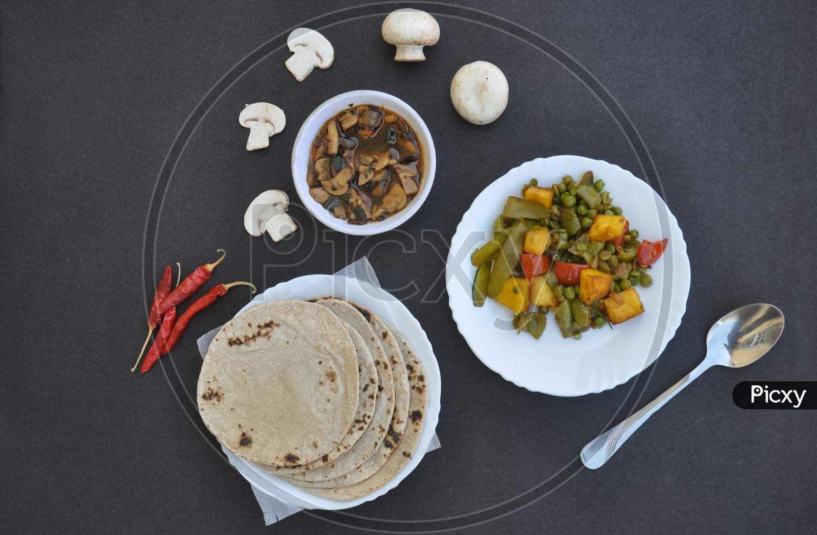 High angle view of matar paneer mix veg, mushroom soup and roti (Indian bread) over black background with copy space with copy space