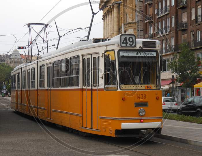 Orange electric tram running through the city of Budapest