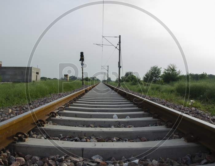 RAILWAY TRACK WITH LIGHT AND ELECTRIC POLE IN LANDSCAPE. INDIAN RAILWAY TRACK IN THE MORNING SUNLIGHT.