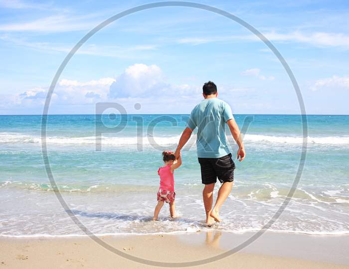 A father and his children walking around the beach.