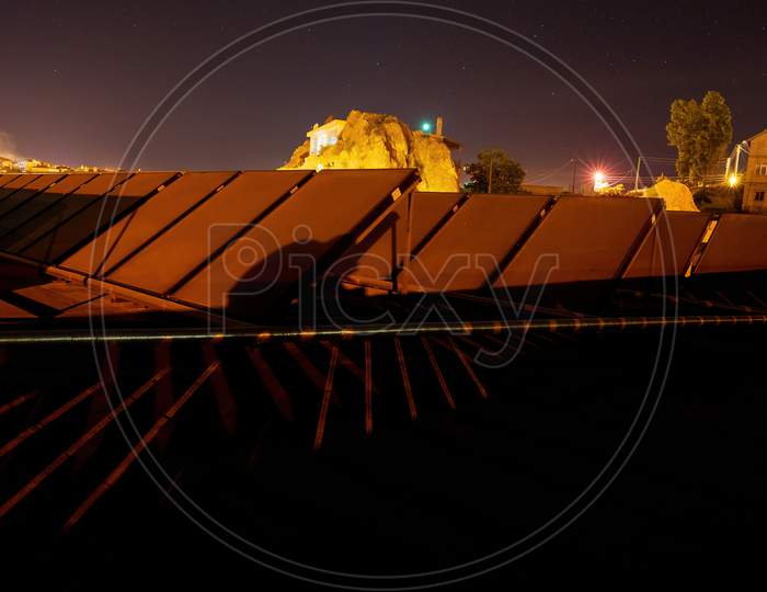Astro Photography Of Solar Panel On A Roof Top Of A Hotel Against Typical Rocks And Starry Sky During Night In Cappadocia, Turkey