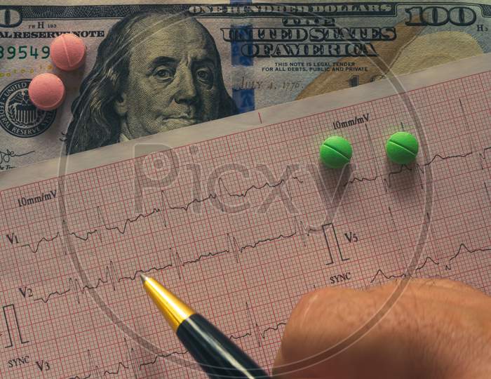 Desk Of A Doctor. Pills Scattered Between Banknotes And Ekg.