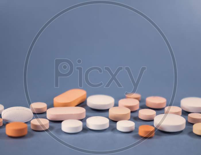 Numerous Pills Of Different Colors On A Neutral Background. Free Space.
