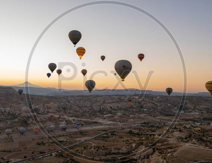 Cappadocia, Turkey - September 14, 2021: Wide Angle Aerial Shot Of Colorful Hot Air Balloons Together Floating In The Sky At Early Morning Sunrise Horizon In Goreme National Park