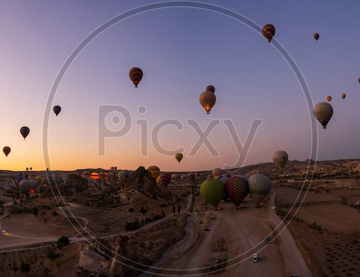 Cappadocia, Turkey - September 14, 2021: Wide Angle Panorama Aerial Shot Of Colorful Hot Air Balloons Together Floating In The Sky At Early Morning In Goreme