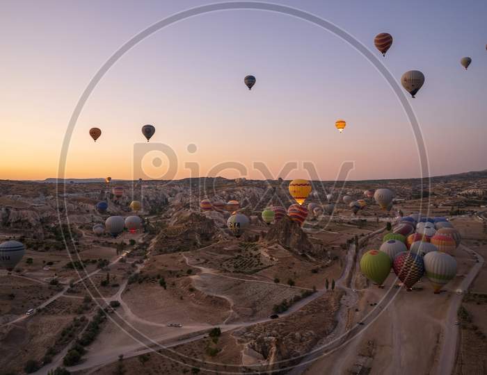 Cappadocia, Turkey - September 14, 2021: Wide Angle Aerial Panoramic Shot Of Colorful Hot Air Balloons Together Floating In The Sky At Early Morning Sunrise Horizon In Goreme National Park