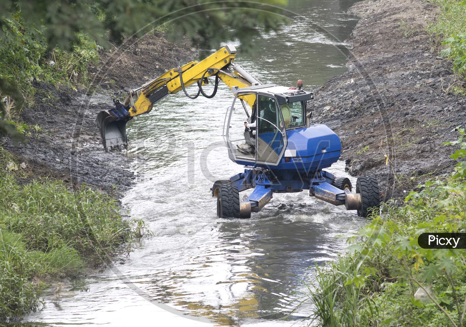 Excavator Performing River Dredging And Clearing Up The River Banks.