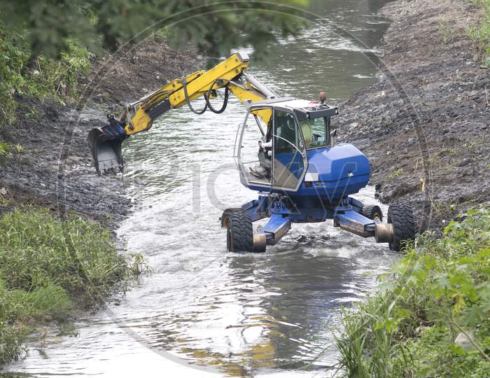 Excavator Performing River Dredging And Clearing Up The River Banks.