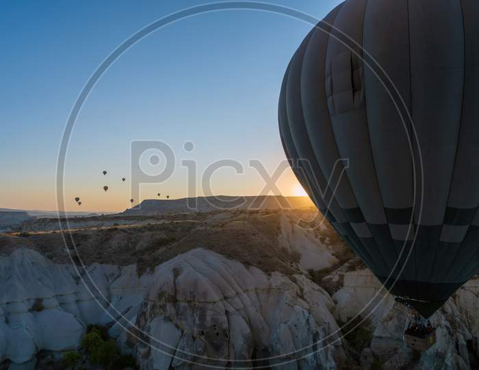 Huge Hot Air Balloon Taking Flight With People Against Sunrise In Famous Cappadocia Located In Anatolia Region Of Turkey