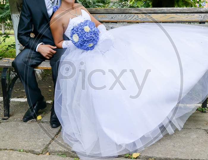 Outdoor Portrait Of Bride And Groom. The Bride Is Holding A Blue Flower Bouquet