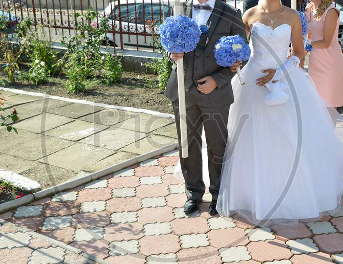 Traditional Romanian Village Wedding. The Bride And Groom Together With The Wedding Guests Are Walking On The Road