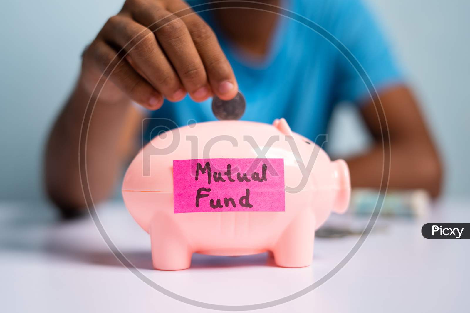 Concept Of Mutual Fund Investment, Showing With Hands Placing Coins Inside The Piggy Bank With Mutual Fund Sticker