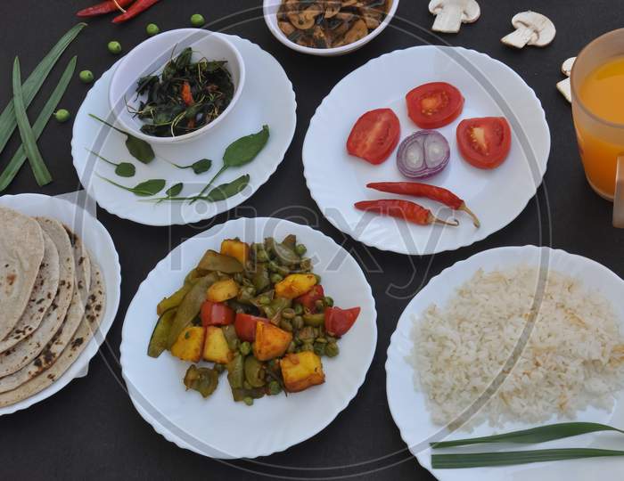 Indian Food: Flat lay of mushroom soup, saag (greens), salad, chapati (Indian bread), matar paneer mix veg, chawal (rice) and juice