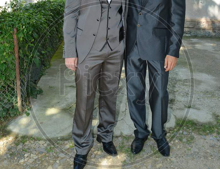 Outdoor Photograph Of Two Wedding Guests Dressed In Toxedo